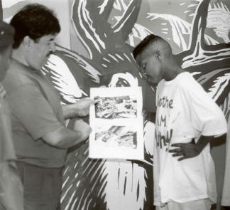 Ruben Guerrer shows a youth the final design for a mural in the Up Bound Project